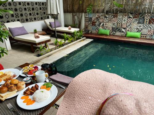a table with plates of food next to a swimming pool at Sarina Hotel & Villa in Phnom Penh