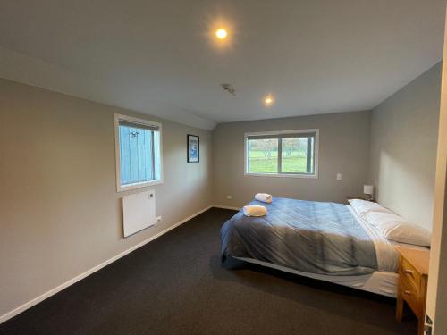 a bedroom with a bed and two windows at Pudding Hill Lodge & Chalets in Mount Hutt