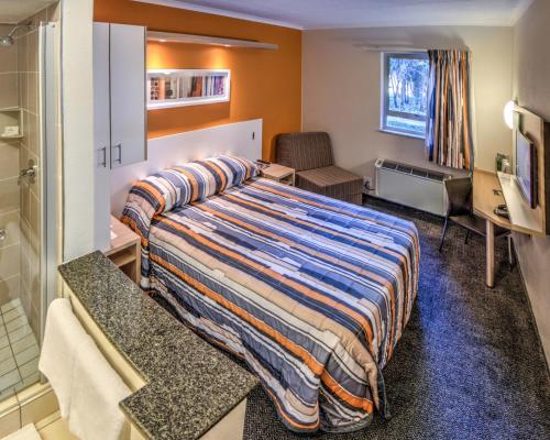 a hotel room with a bed and a bathroom at Road Lodge Germiston in Germiston