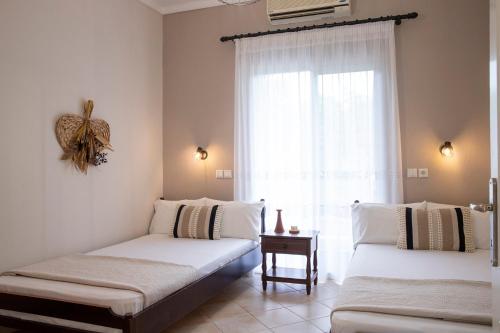 two beds in a room with a window at Elena luxury living in Paralía Skotínis