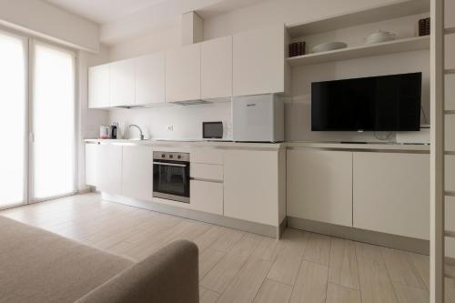 eine Küche mit weißen Schränken und einem Flachbild-TV in der Unterkunft Casa Aleardi grazioso e nuovissimo monolocale con balcone in Pesaro