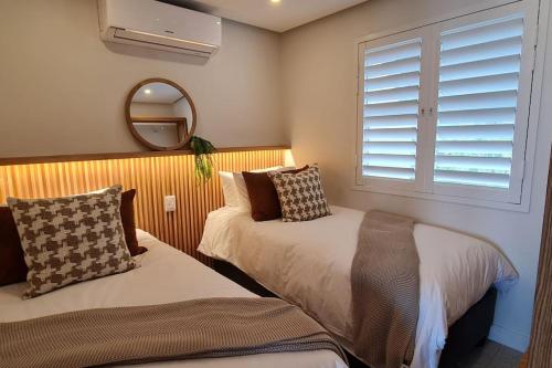 a bedroom with two beds and a mirror and a window at 25 Chaka's Cove in Ballito