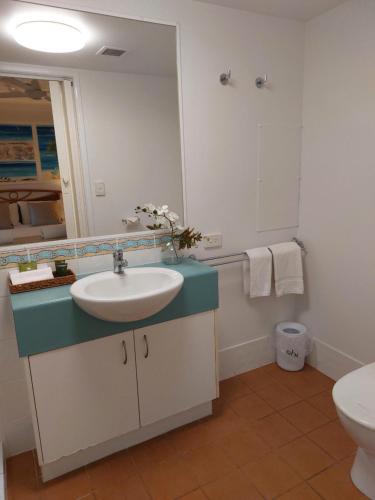 a bathroom with a sink and a toilet and a mirror at Sandy Shores Holiday Units in Caloundra