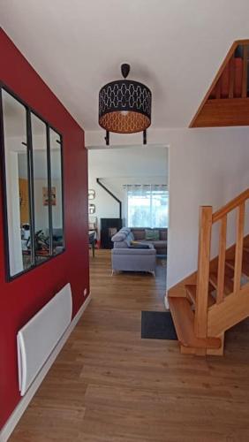 un salon avec un mur rouge et un escalier dans l'établissement Maison entre Terre & Mer – Wifi, à Loctudy