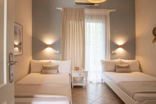 two beds in a room with a window at Elena luxury living in Paralía Skotínis