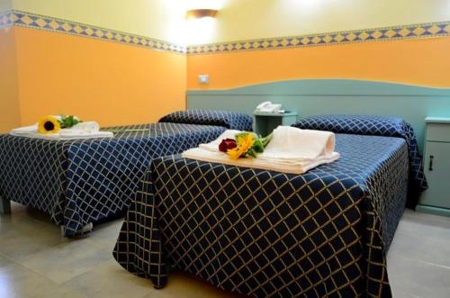 two beds in a room with blue and yellow at HOTEL LE PALME in SantʼAnna Arresi