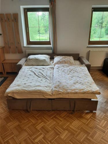 a large bed in a bedroom with two windows at Schöne Wohnung am Bauernhof in Lehen