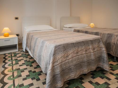 Zimmer mit 2 Betten und einem Tisch mit Lampen in der Unterkunft PESCIOLINO B&B in Mola di Bari