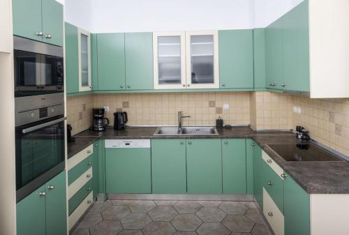 a kitchen with green cabinets and a sink at Sensia villa with Hot tub and Caldera View in Oia