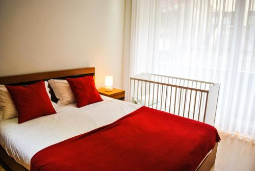 a bedroom with a red and white bed with a window at Apartamentos Portodouro - Santa Catarina in Porto