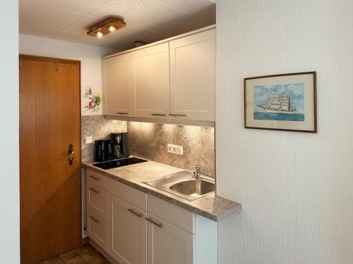 eine Küche mit weißen Schränken und einem Waschbecken in der Unterkunft Haus *Üüs Aran* Wohnung Nr. 3 in Nebel