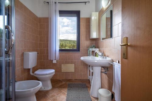 a bathroom with a sink and a toilet and a window at Casa Vacanza Baratz 4 in Alghero