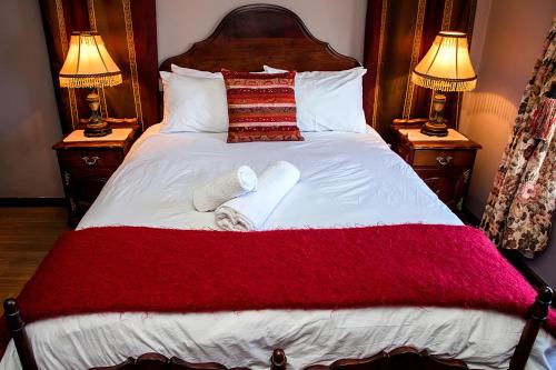 a bed with a red and white blanket and two lamps at aHa Guest House in Sea View