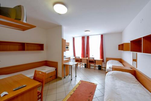 デブレツェンにあるキャンパス ホテルのベッド2台、デスク、テーブルが備わる客室です。