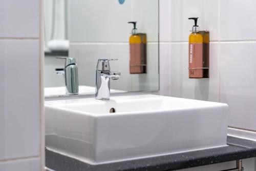 a bathroom with a white sink and a mirror at Heeton Concept Hotel - City Centre Liverpool in Liverpool