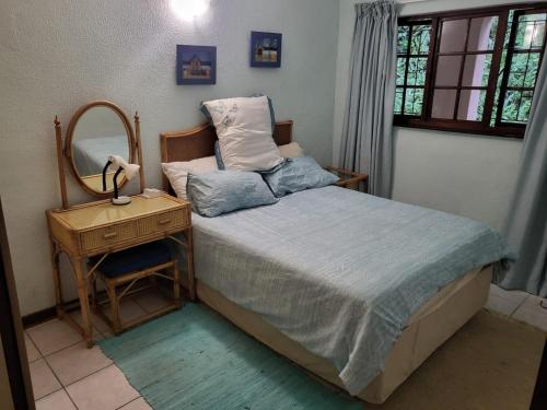a bedroom with a bed with a mirror and a table at Eden Wilds 30 in Port Edward