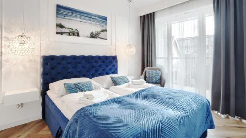 a bedroom with a blue and white bed and a window at Prywatne apartamenty Sun & Snow w obiekcie Ustronie Apartments in Ustronie Morskie