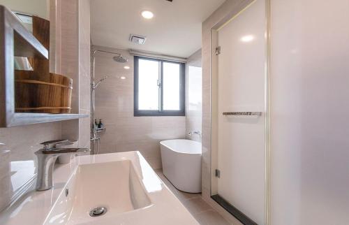 a white bathroom with a sink and a shower at 幸福海衝浪民宿 in Toucheng