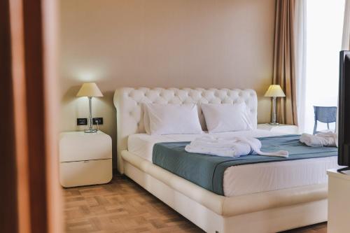 1 dormitorio con 1 cama con sábanas y almohadas blancas en Rapo's Resort Hotel, en Himare