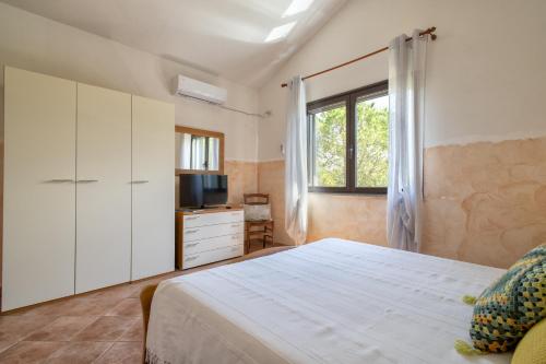 a bedroom with a bed and a tv and a window at Casa Vacanza Baratz 3 in Alghero