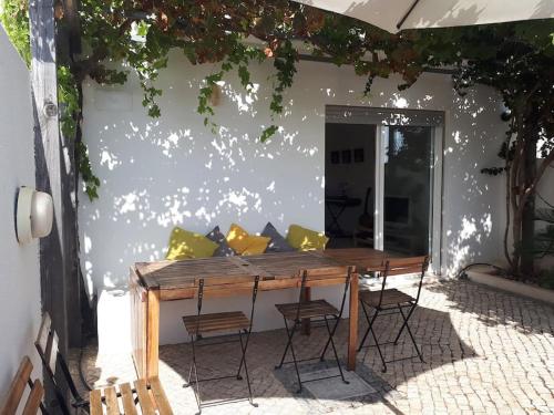 a wooden table with chairs in a patio at Casa Monte Sol in Vila Nova De Cacela