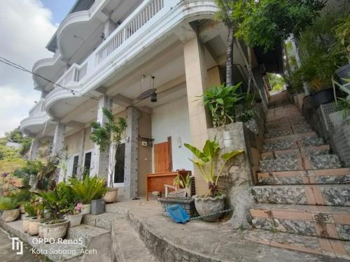 IboihにあるFURQAN GUEST HOUSE Familyの階段と植物が目の前にある家