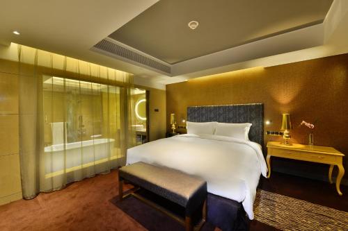 a bedroom with a large white bed and a bathroom at Sofitel Zhengzhou International in Zhengzhou