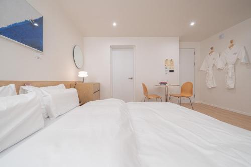 a white bedroom with a large white bed and a table at Aank Hotel Cheongju Uam 1st in Cheongju