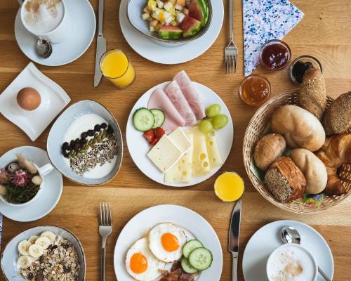 a wooden table topped with plates of breakfast food at Sopherl am See - Frühstück auf der Seeterrasse, sehr ruhig und wunderschön am See, 3 Minuten nach Oberpfaffenhofen, viele Radtouren, Restaurants & Cafes in der Umgebung in Weßling