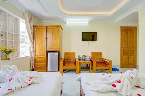 a room with two beds and a table and a kitchen at The Moment - Quang Anh Hotel Vũng tàu in Vung Tau