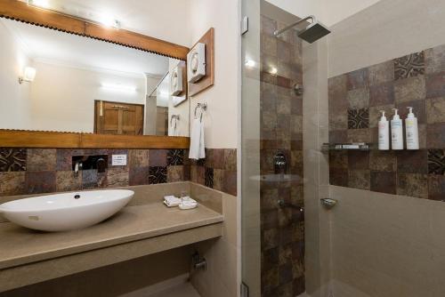 a bathroom with a sink and a shower at The Anantmaya Resort in Manāli