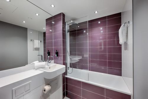 ein Badezimmer mit einem Waschbecken und einer Dusche mit lila Fliesen in der Unterkunft Premier Inn Regensburg City Centre in Regensburg