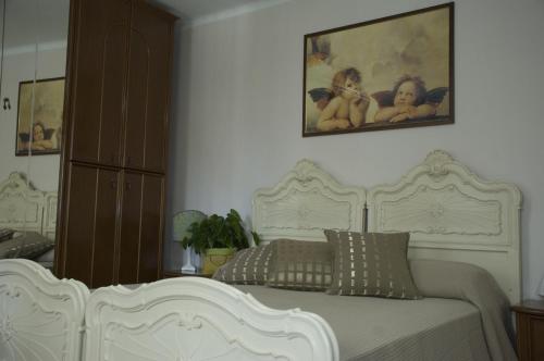 キエーリにあるIl Cortile Della Nonnaの白いベッドと壁に絵画が飾られたベッドルーム1室