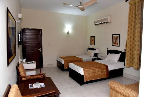 a hotel room with two beds and a couch at Herfa INN Hotel Lahore in Lahore