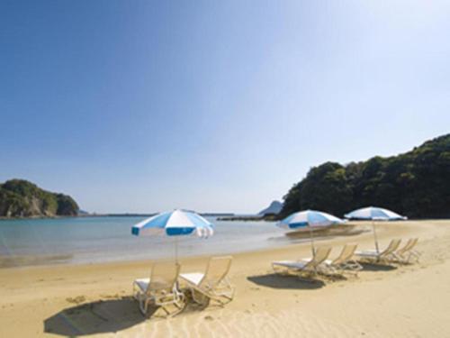 a group of chairs and umbrellas on a beach at Nichinankaigan Nango Prince Hotel in Nichinan