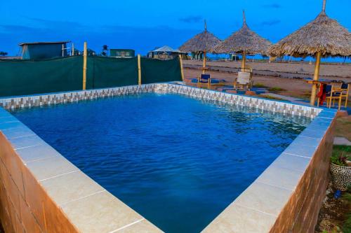 a swimming pool at the beach with umbrellas at Little Amanya Camp in Amboseli