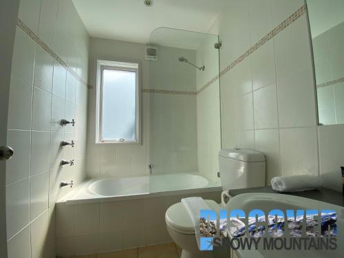 uma casa de banho branca com uma banheira, um WC e um lavatório. em Three Bears 3 em Thredbo