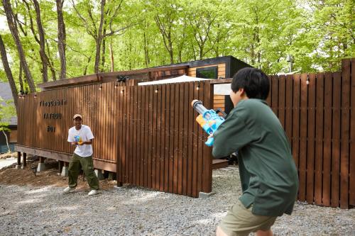 two men standing in front of a wooden building at サウナバーベキュージャグジー完全貸し切りという贅沢大人の秘密基地#01 in Miyota