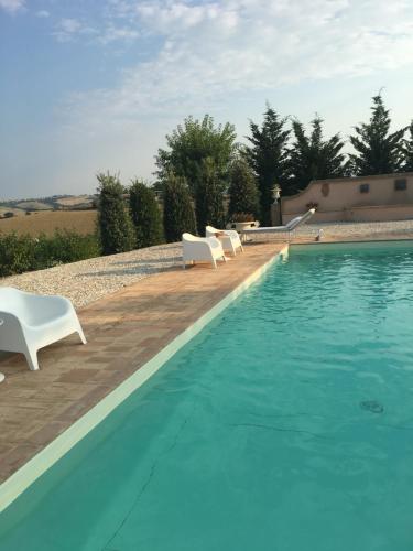 a swimming pool with two white chairs next to it at Relais Il Margarito in Montefano