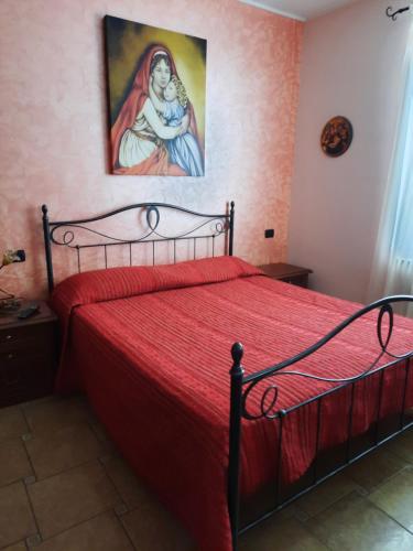 Un dormitorio con una cama roja con una pintura en la pared en B&B Cuoreverde Pollino en Rotonda
