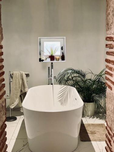 a white bath tub in a bathroom with plants at Maison restaurée avec piscine in La Sauvetat-sur-Lède