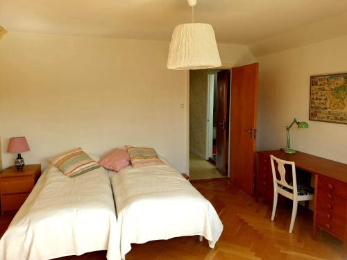 a bed in a bedroom with a desk and a chair at Egen ovanvåning i charmig villa nära havet in Ystad