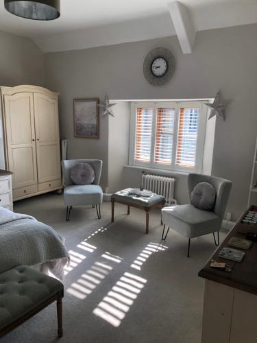 a bedroom with two chairs and a table and a clock at The Skreen in Builth Wells
