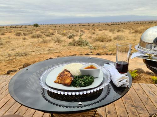 Un plato de comida en una mesa con una copa de vino. en Little Amanya Camp, en Amboseli