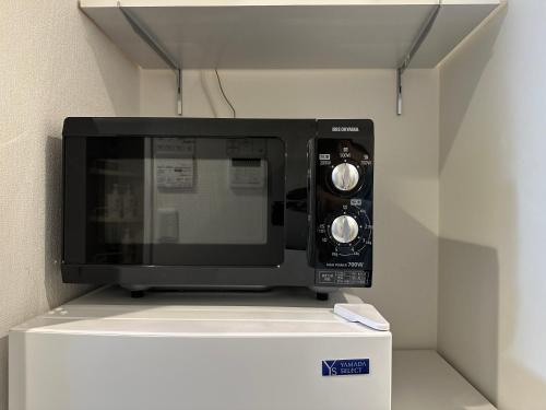 a microwave oven sitting on top of a shelf at nestay inn tokyo kagurazaka in Tokyo