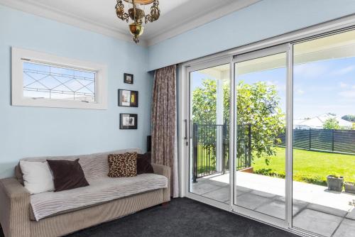 a living room with a couch and a sliding glass door at Live Large in the Village in Havelock North
