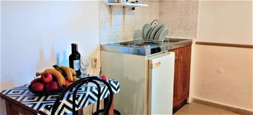 a kitchen with a table with a bowl of fruit and a sink at Eleni Apartments Sant George Beach in Agios Georgios