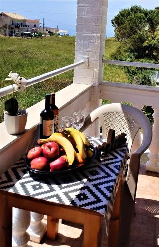 a plate of fruit on a table on a porch at Eleni Apartments Sant George Beach in Agios Georgios