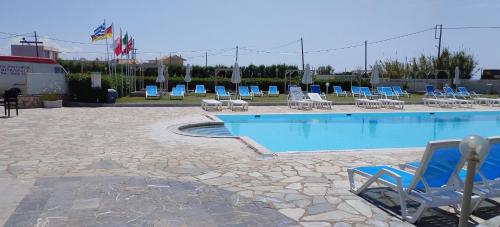 a swimming pool with blue chairs and a bunch ofitures at Eleni Apartments Sant George Beach in Agios Georgios