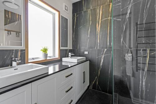 a bathroom with a white sink and a mirror at Live Large in the Village in Havelock North
